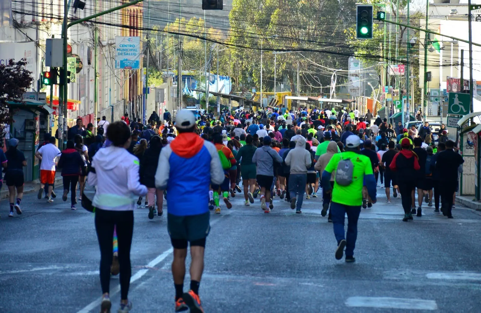 Participantes de La Paz 10K corriendo cuesta arriba por el centro de La Paz, Bolivia, de espaldas, al amanecer
